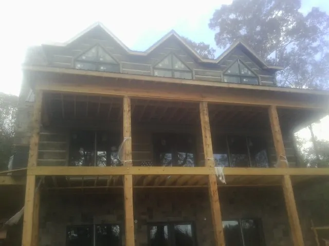 Dormers and porch framing on a large log home under construction — Roof Coating work by our crew in Lancaster